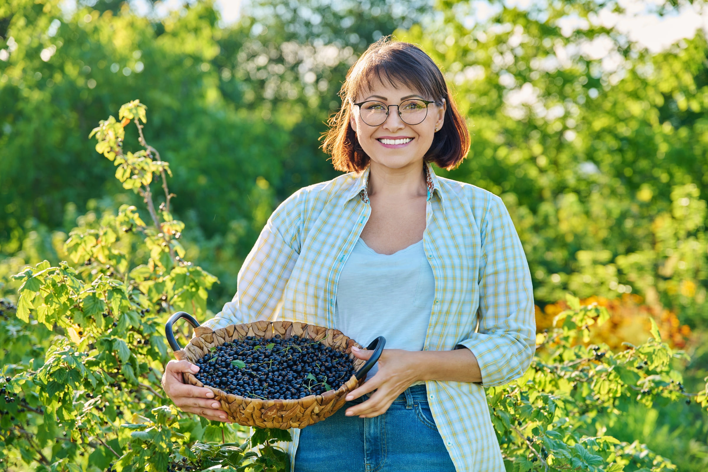 smiling-middle-aged-woman-holding-basket-ripe-blackcurrants-szh